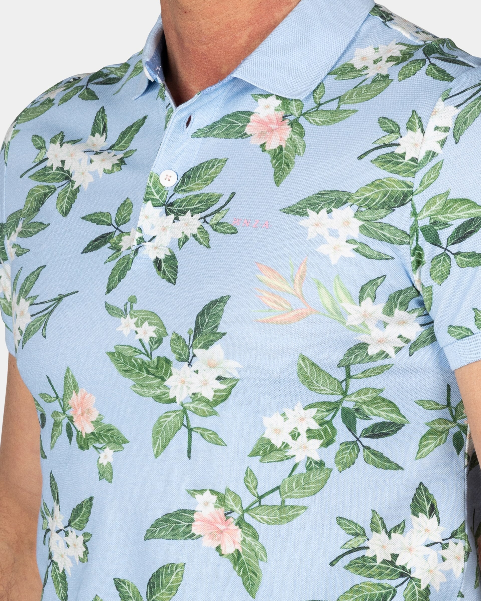 Pastelblauwe polo met grote bloemenprint Pastelblauwe polo met grote bloemenprint